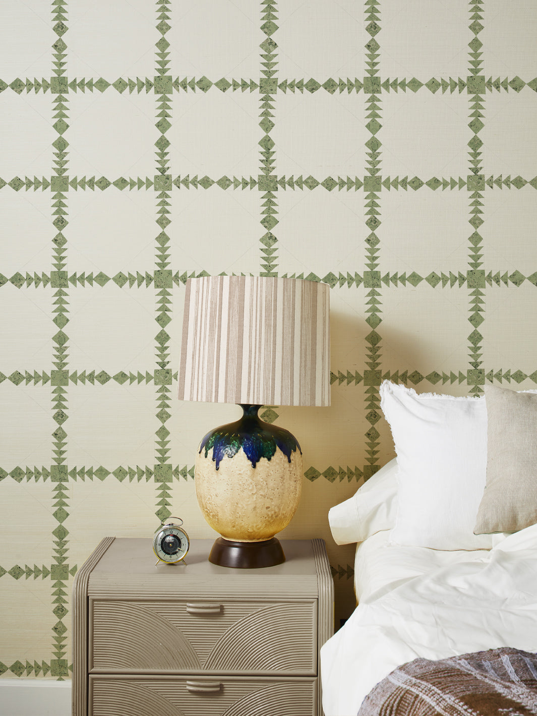 Green geometric grasscloth wallpaper with cross lattice pattern behind bed