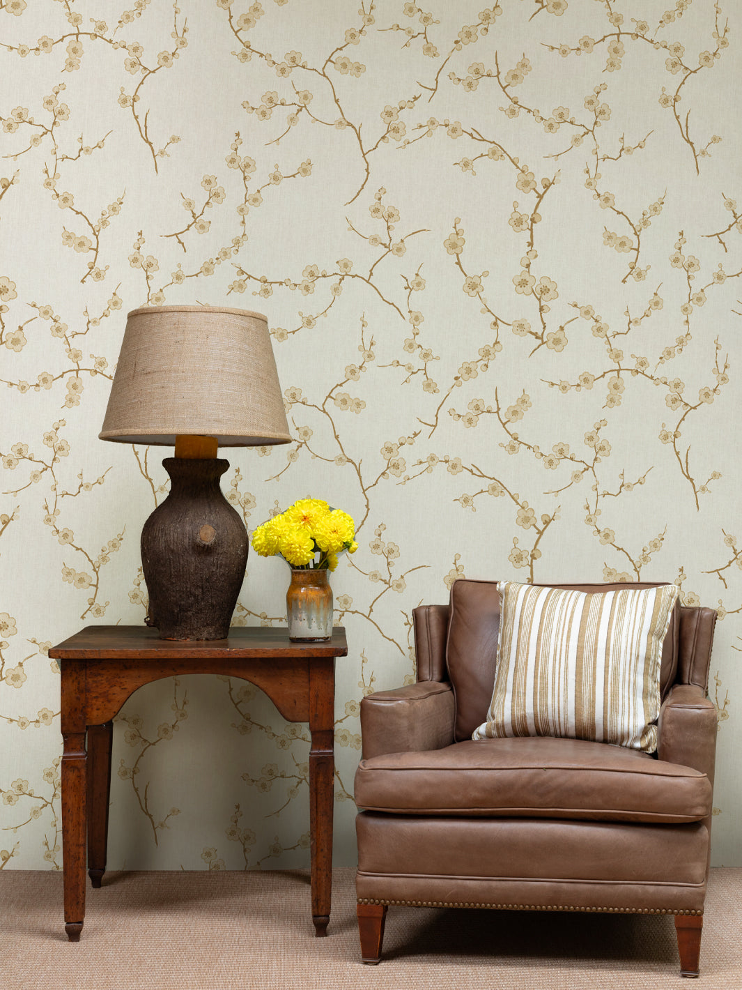 Wallpaper on wall featuring gold cherry blossom vines and small blossoms on light beige