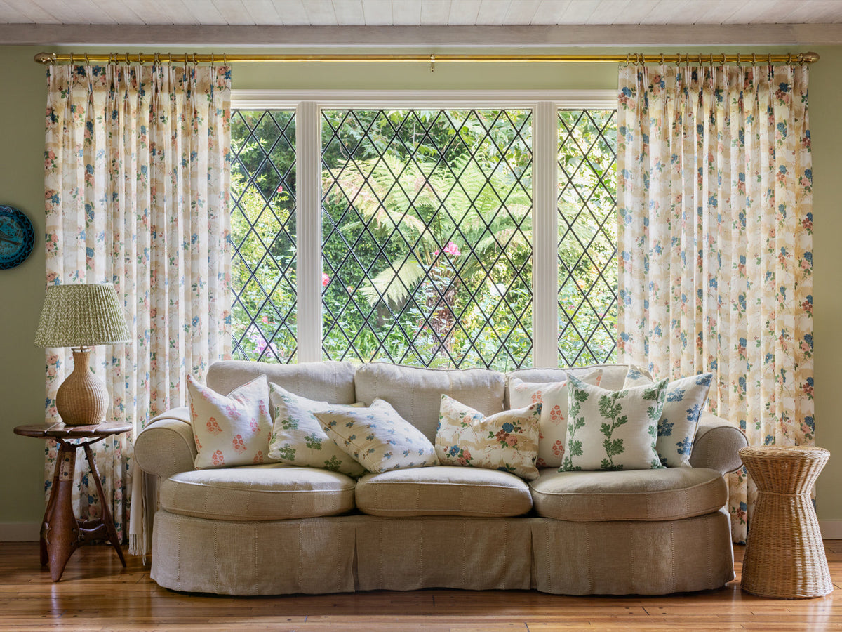 Floral chintz fabric on curtains and sofa cushions, beige with blue and pink blooms