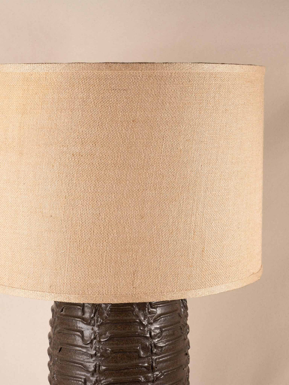 Mid-century brown ceramic table lamp with a textured, ribbed geometric base and burlap shade