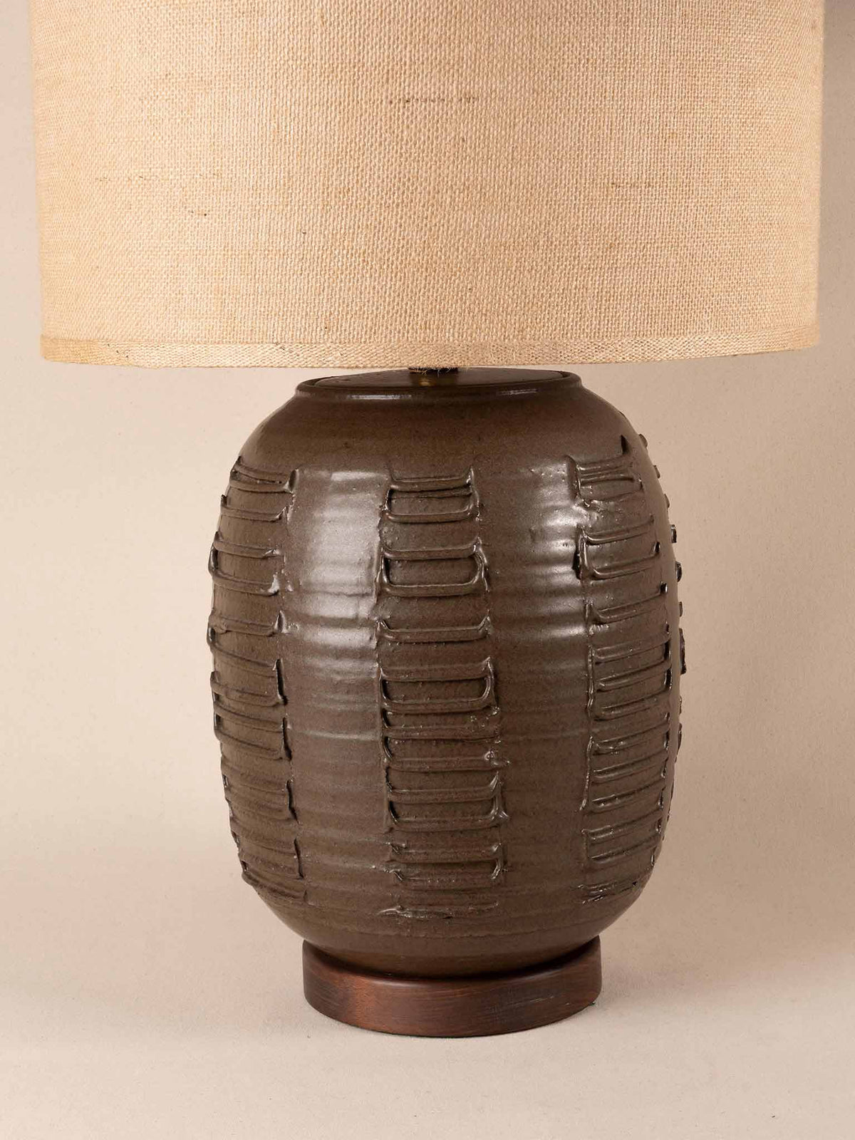 Mid-century brown ceramic table lamp with a textured, ribbed geometric base and burlap shade
