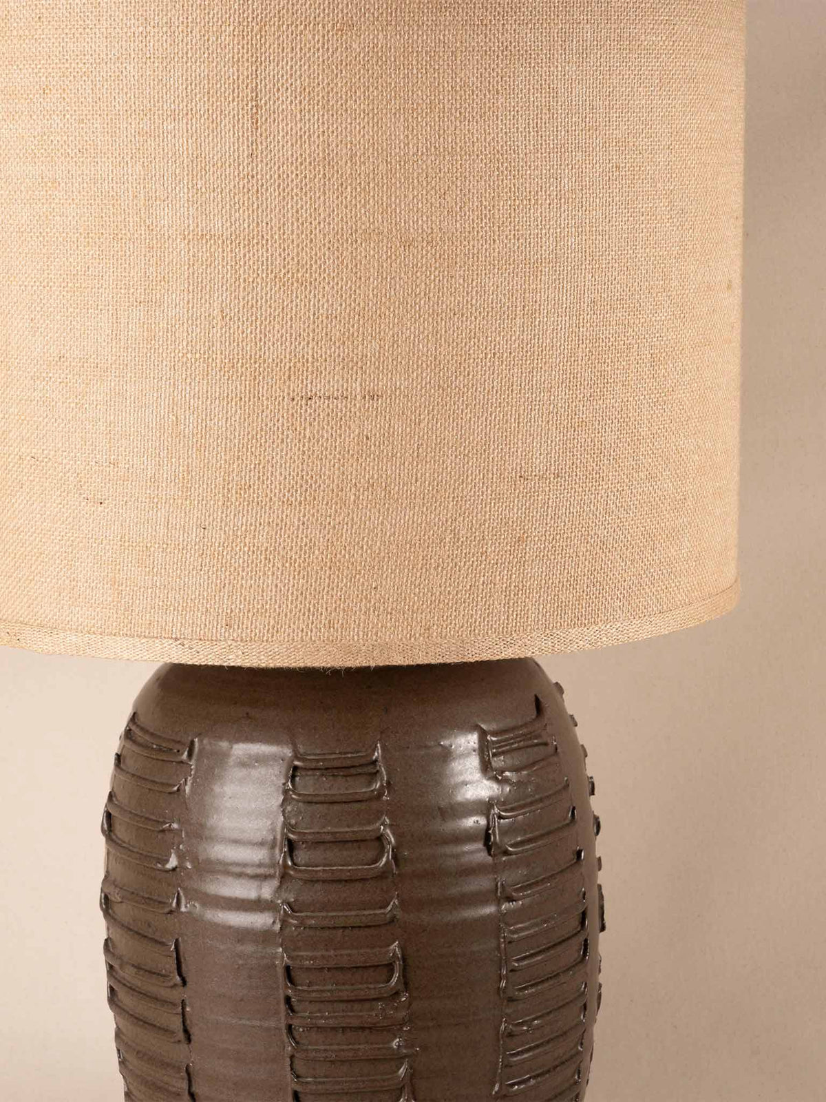 Mid-century brown ceramic table lamp with a textured, ribbed geometric base and burlap shade