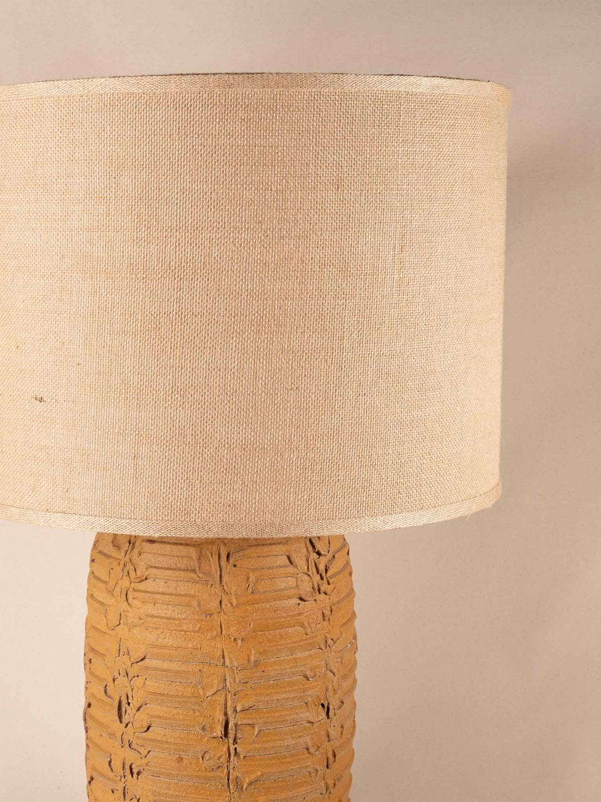Tall mid-century yellow ceramic table lamp with a textured, ribbed geometric base and burlap shade