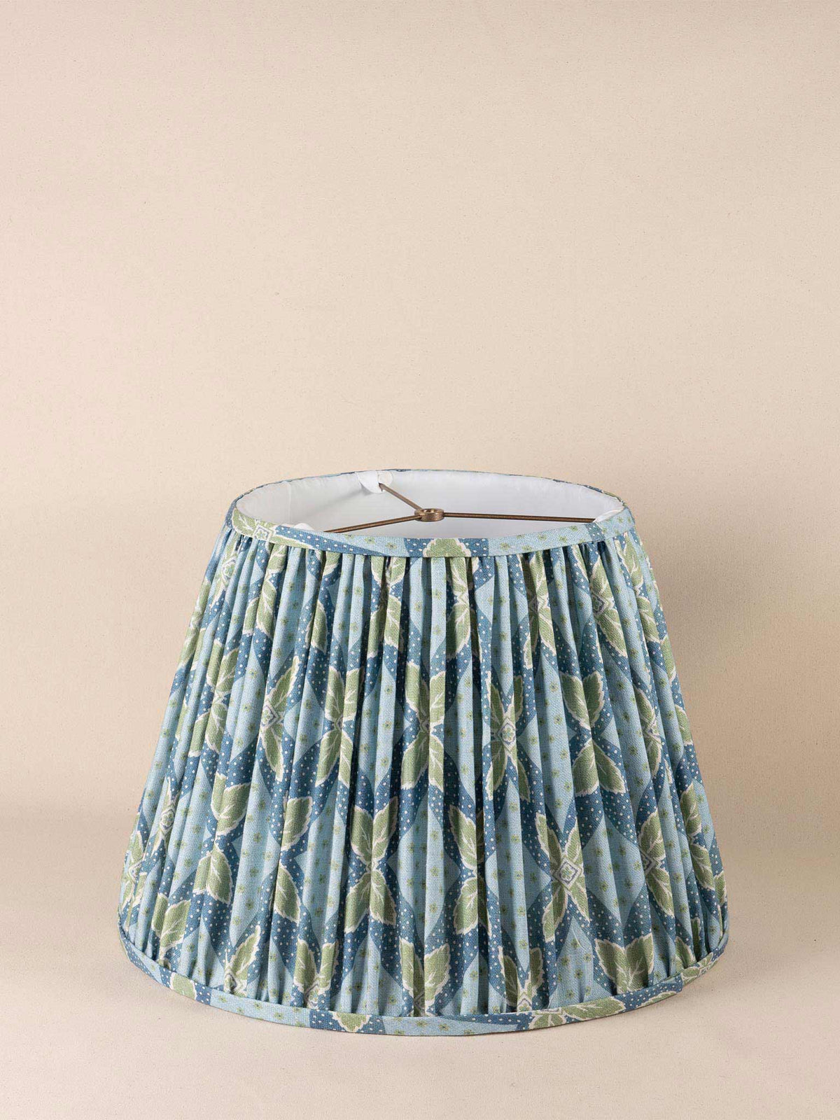 Table lamp with a round woven bamboo base and a pleated blue and green patterned cone shade