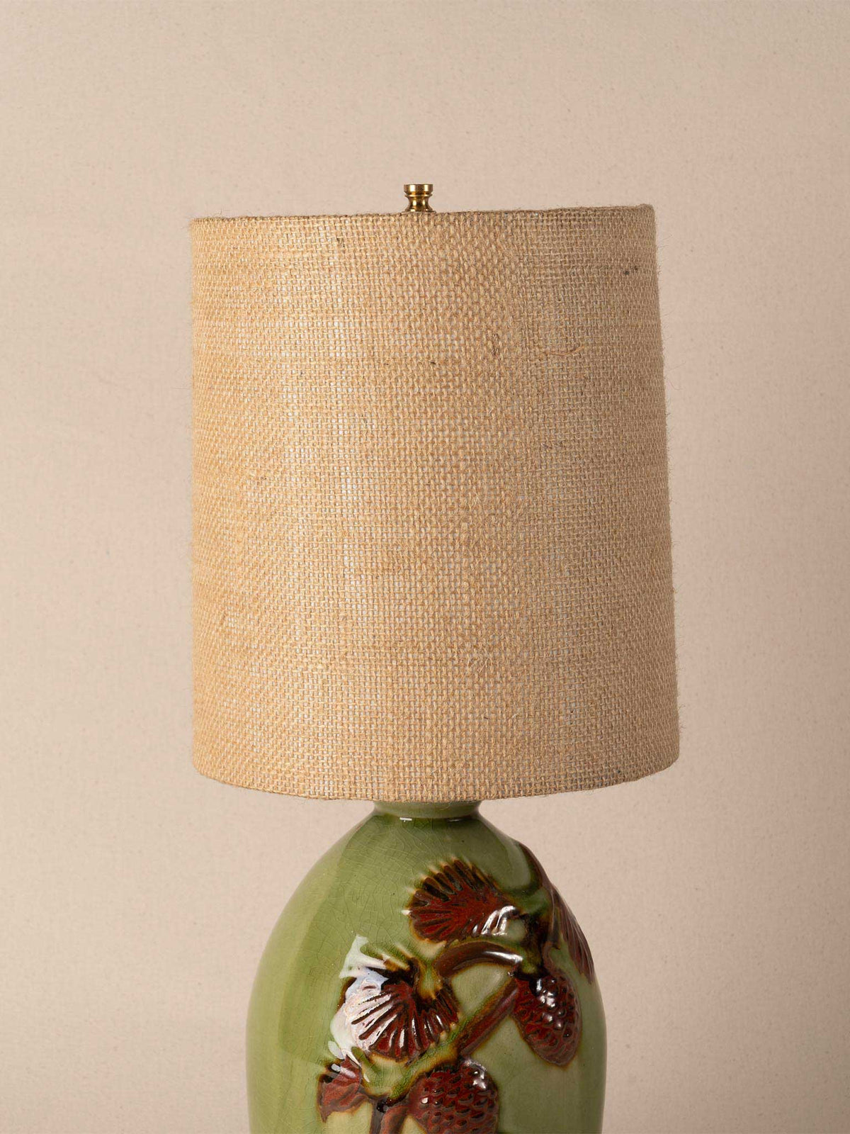 Green ceramic table lamp with raised pinecone motif and burlap drum shade