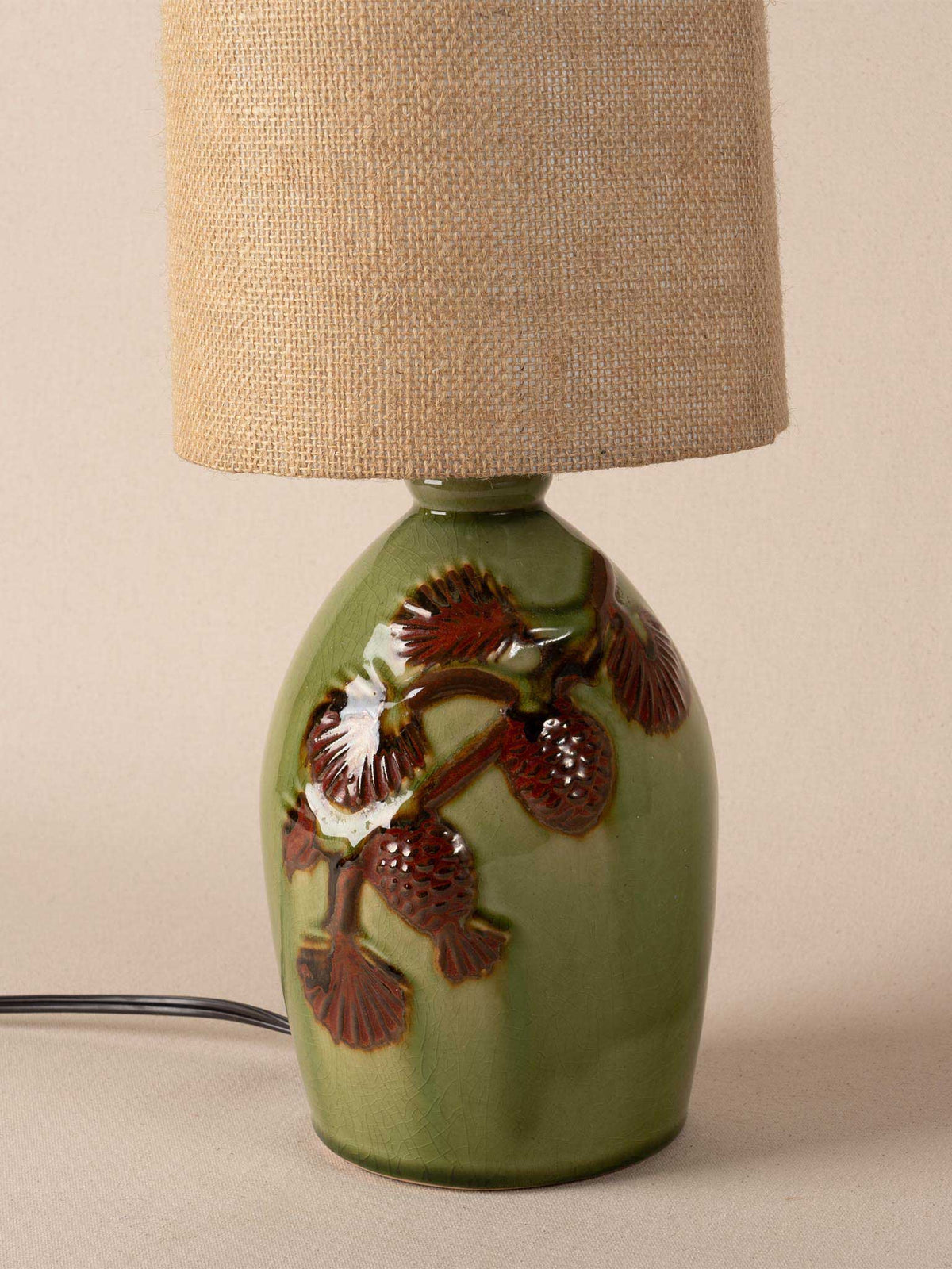 Green ceramic table lamp with raised pinecone motif and burlap drum shade