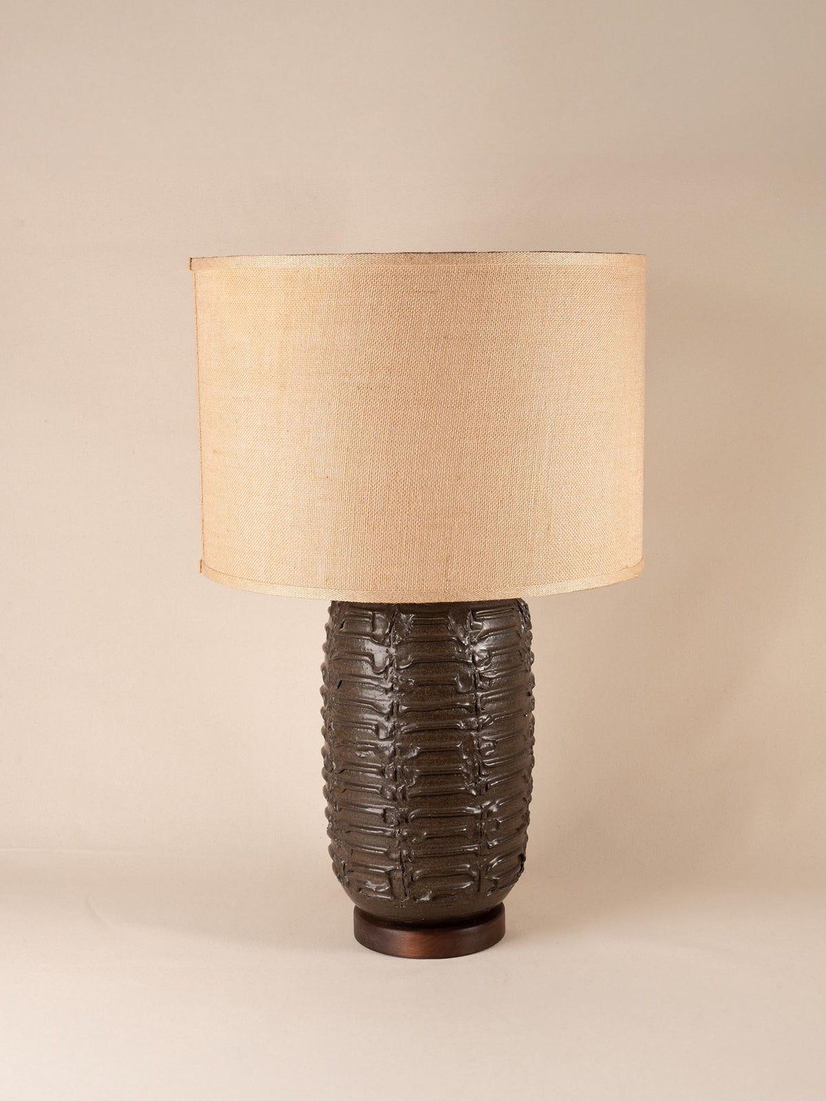 Mid-century brown ceramic table lamp with a textured, ribbed geometric base and burlap shade
