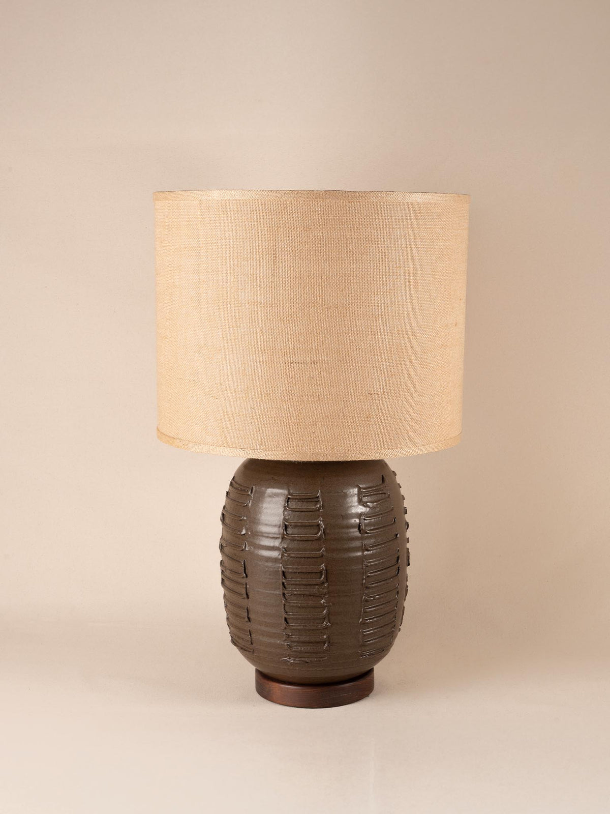 Mid-century brown ceramic table lamp with a textured, ribbed geometric base and burlap shade