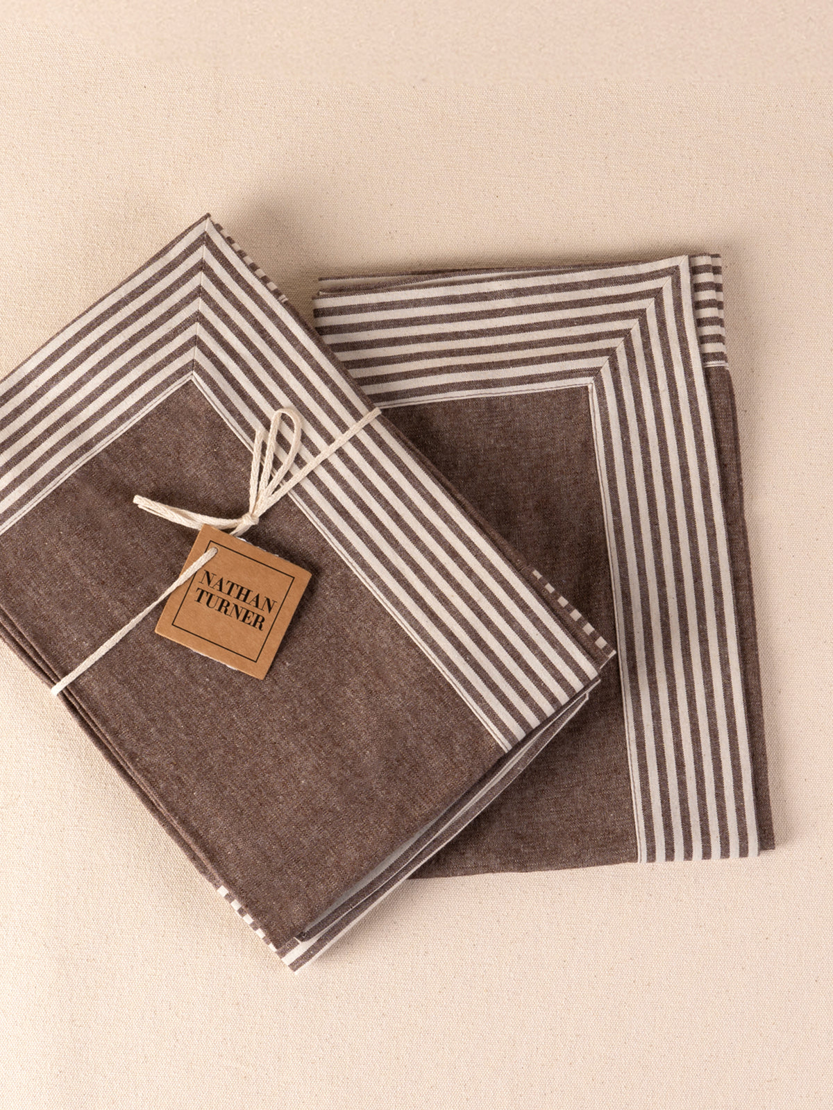 Four folded cotton napkins in chestnut tones
