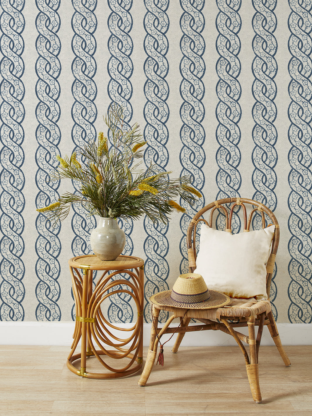 Grasscloth wallpaper showing repeating dark blue floral loop motifs on speckled light field